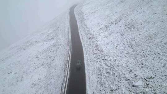 航拍在下雪天行驶在山路上的车辆