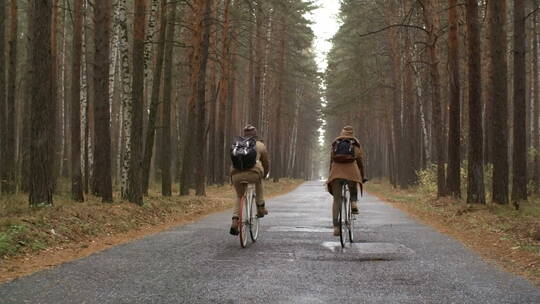 下雨天夫妇骑自行车经过森林公路