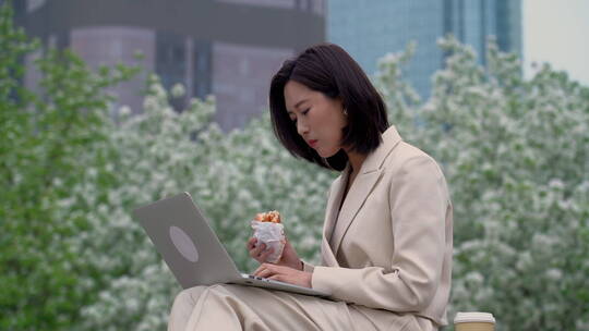 商务女性在户外边吃饭边用电脑