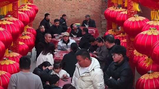 人群围坐红灯笼下聚餐场景