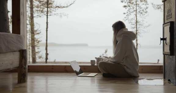 女人在有风景的小屋里用笔记本电脑打字