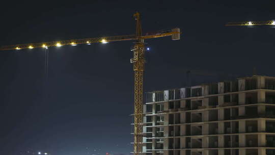 夜间建筑施工.延时摄影.带照明的建筑工地塔式起重机
