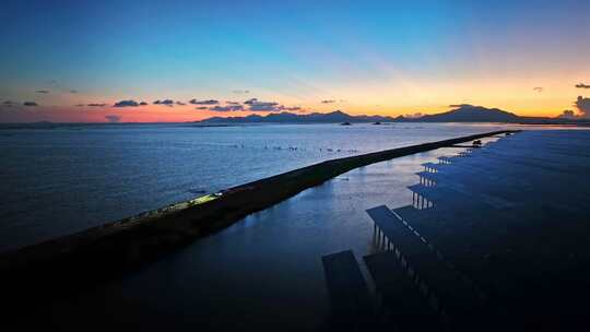 航拍夕阳下汽车开灯行驶在有晚霞的海边