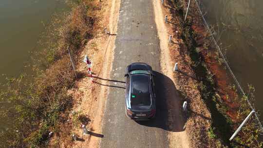 汽车行驶在稻田中间的乡村道路上，无人机视