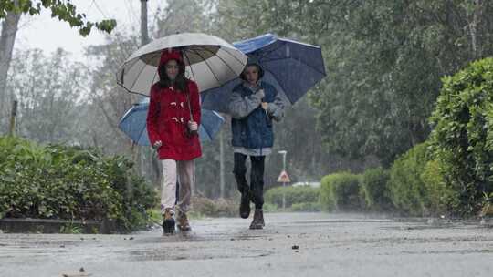 孩子们拿着雨伞在雨中蹦蹦跳跳地走在路上