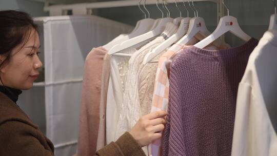 中年女性在服装店衣柜选择衣服