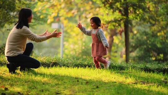 秋天公园小女孩拿树叶跑向妈妈亲子陪伴成长