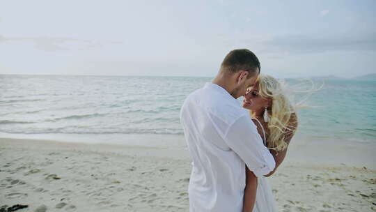 爱年轻的夫妇拥抱上一个有风的海滩慢动作