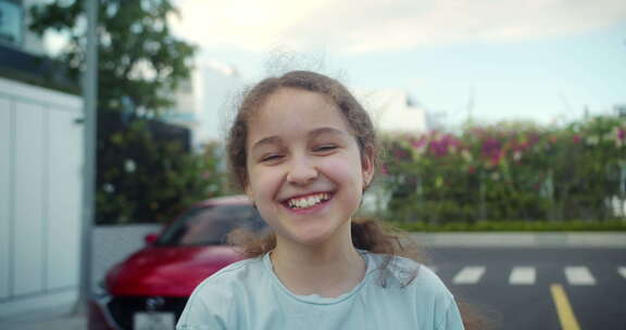 肖像快乐的孩子积极的小女孩在街上靠近房子