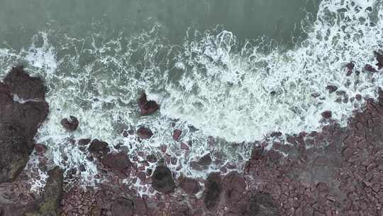 海岸礁石沙滩海水拍打礁石阴天海滩海浪冲刷视频素材模板下载