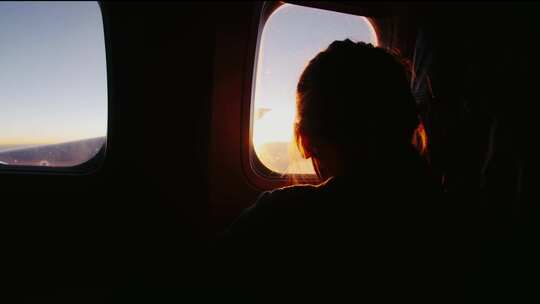 快乐的小女孩透过飞行飞机的窗户看
