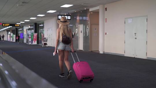 女孩在机场拉着皮箱行走
