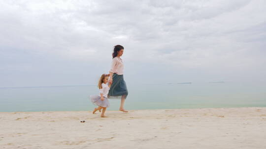妈妈牵着女儿在沙滩上奔跑
