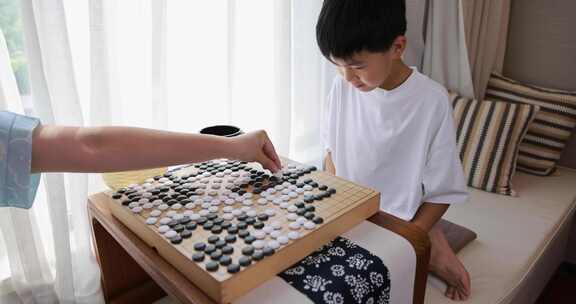 可爱的男孩在窗边下围棋