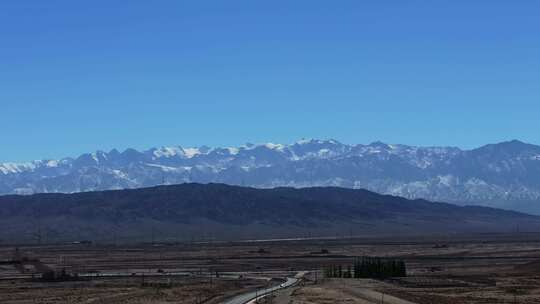 大气航拍西北戈壁滩上的公路及远方的雪山