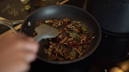 女性手搅拌煎锅内食物特写