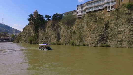 第比利斯库拉河上漂浮的船上的游客，背景是梅特基教堂