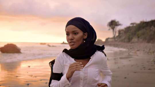 日落时分在海滩上慢跑的索马里裔美国妇女