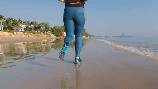 运动女人沿着海滩慢跑的后视图
