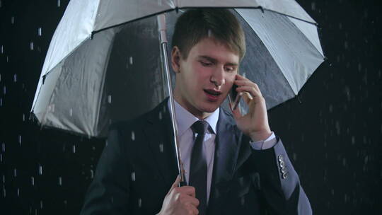 男人在雨中撑伞打电话