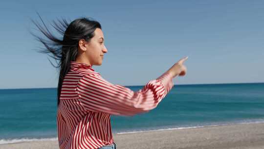 女人用手指指着海边