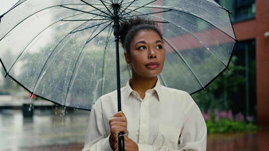 非洲裔美国妇女拿着雨伞和平地环顾四周天气