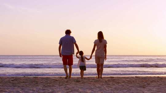 幸福的一家人三口海边散步看夕阳晚霞