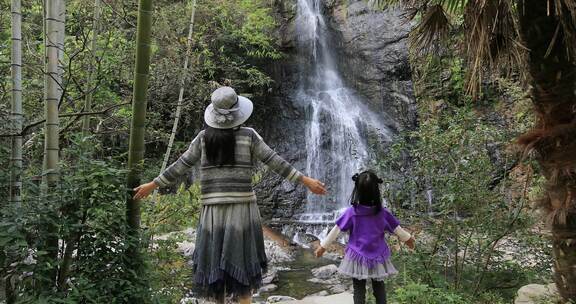 妈妈与女儿一起拥抱大自然背影 面对瀑布