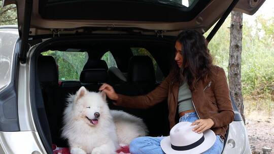 女孩和狗坐在汽车后备箱中