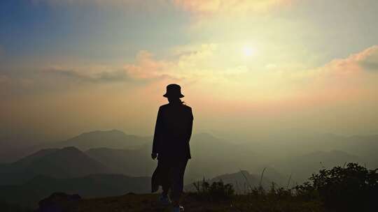 一个女性在山顶夕阳下行走背影剪影