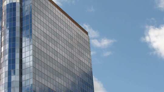 蓝天下的商业楼玻璃幕墙映照着白云流动视频素材模板下载