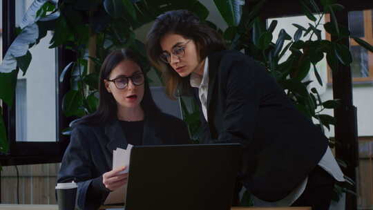 戴眼镜的年轻女商人与同事讨论报告中概述的视频素材模板下载
