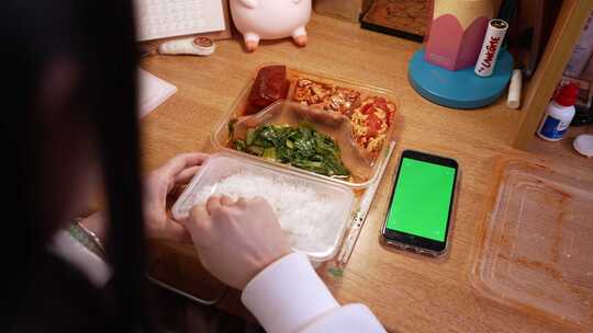 大学生在宿舍吃盒饭手机点外卖