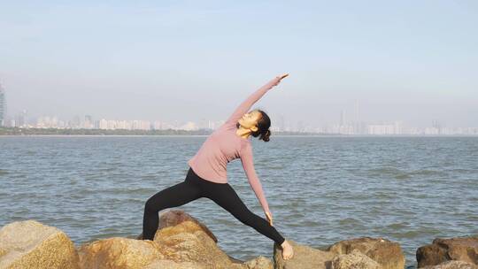 深圳海边练习瑜伽拉升放松的都市白领女性