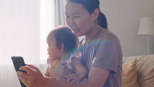 母亲抱着女儿看手机视频素材模板下载