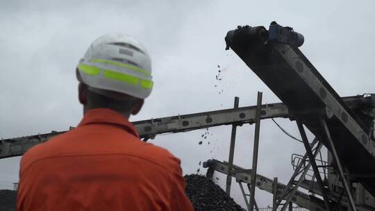 一名煤矿工人观察煤矿开采过程的背面视图