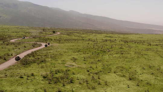 Ser附近恩戈罗恩戈罗山脊山上一条尘土飞扬的道路，游猎旅游车经过长颈鹿视频素材模板下载