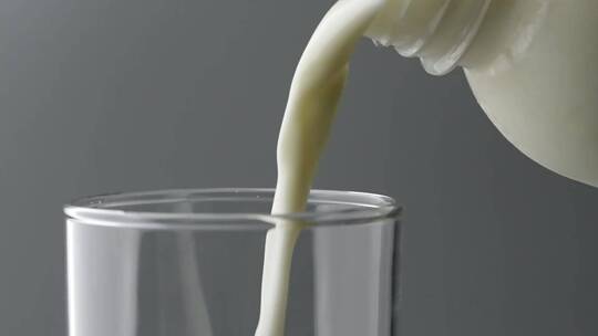 慢镜头拍摄瓶中牛奶饮品倒入玻璃杯