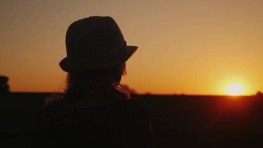 站在夕阳前戴着帽子的女人