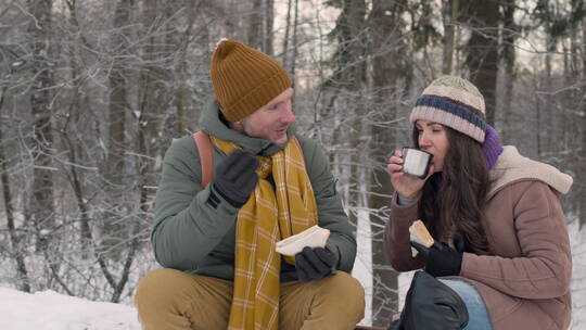 夫妻在雪地里吃三明治喝茶