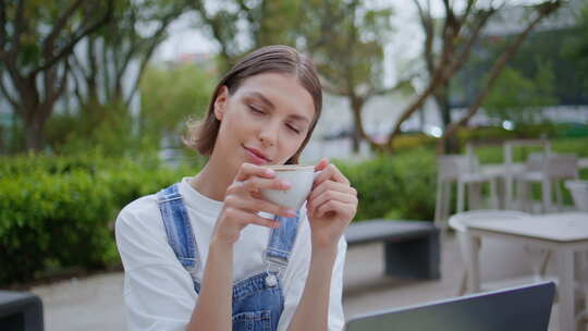 无忧无虑的女孩在户外咖啡馆享受咖啡特写放