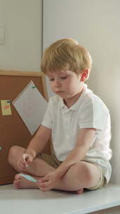 赤脚蹒跚学步的孩子用笔记固定别针检查一张