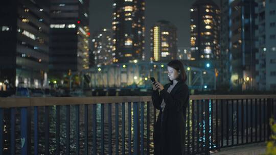年轻的女人在城市里玩手机