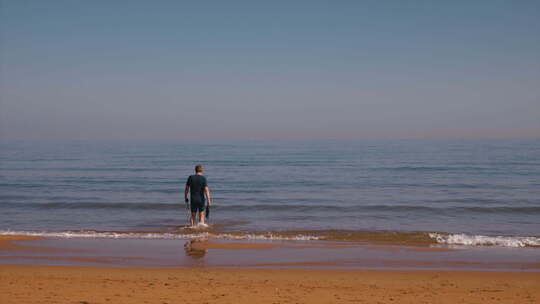 男人从沙滩慢慢走向大海视频素材模板下载