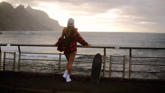女孩站在栏杆上看海
