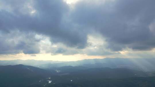 航拍群山间阳光穿透云层的壮阔自然景观