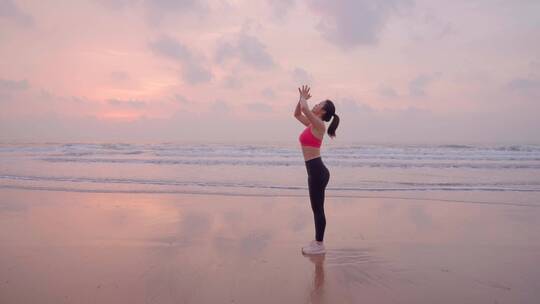 清晨海边美女迎着朝阳练习瑜珈