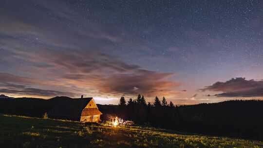在宁静的夏夜大自然星空中与朋友坐在小屋旁