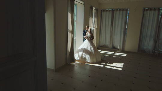 穿着礼服站在窗边的新郎新娘