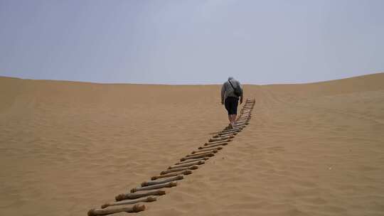贫瘠沙漠沙丘上徒步旅行孤独男人攀登背影